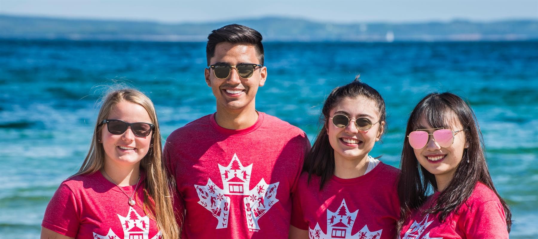 International students wearing NSISP shirts by the ocean in Nova Scotia